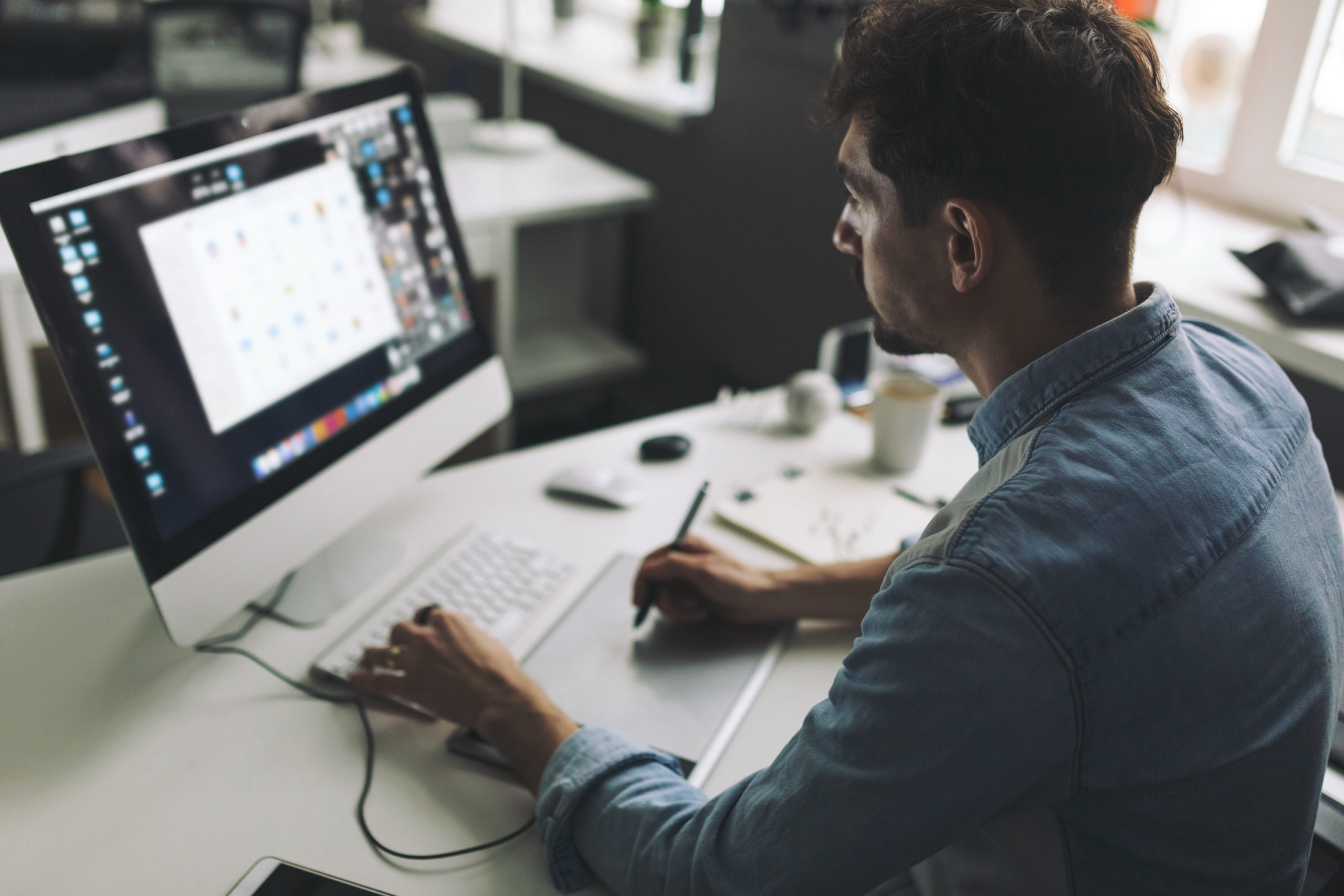 Modern designer sitting in front of computer and working in office